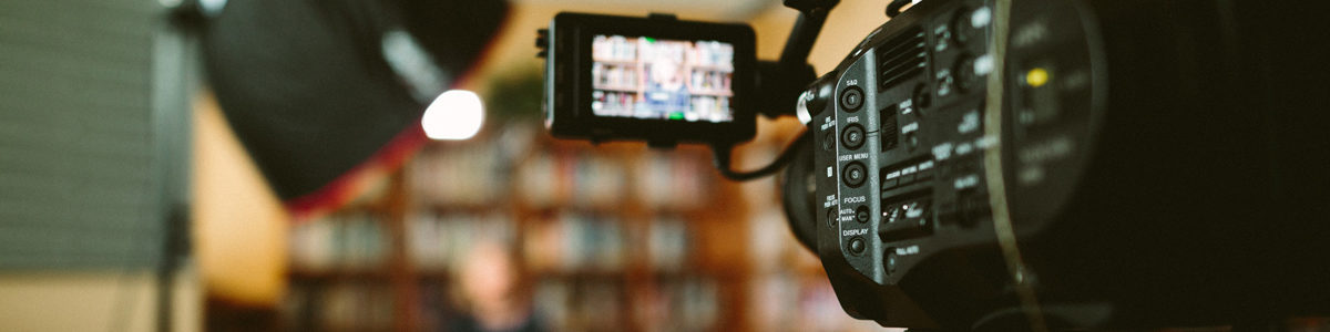 Woman being filmed in a library. Photo by Sam McGhee on Unsplash